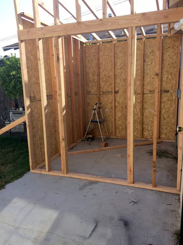 Wooden framed shed structure with OSB sheathing and exposed studs under construction