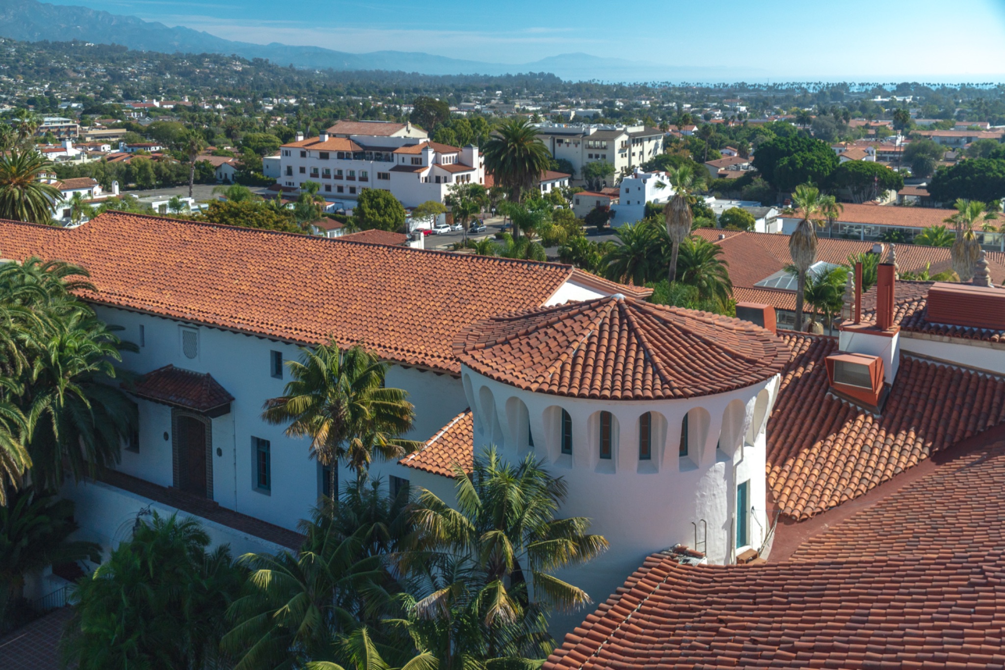 Aerial view of Spanish Colonial architecture with white buildings and terra cotta tile roofs in a hillside community