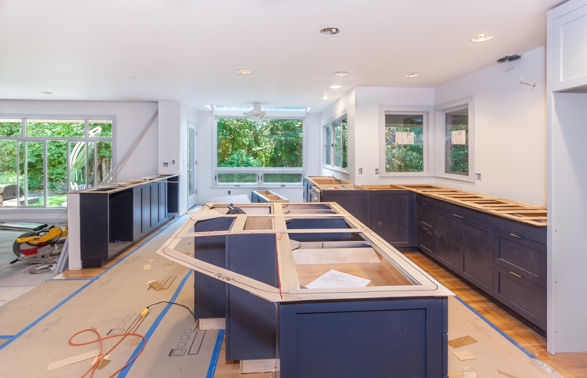 Kitchen renovation in progress with dark cabinetry, wood countertops, and large windows overlooking garden